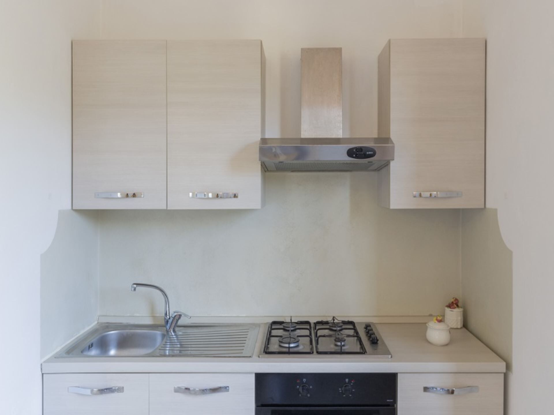 A kitchen with light wood cabinets, a stainless steel sink, a gas stove, and a dishwasher.