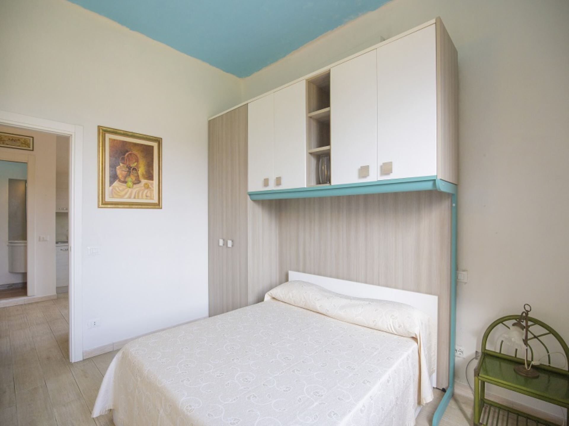 A bedroom with a bed, a wardrobe, and a painting on the wall.