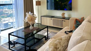 Ein modernes Wohnzimmer mit Sofa, Couchtisch, Fernseher und Blick auf die Stadt.