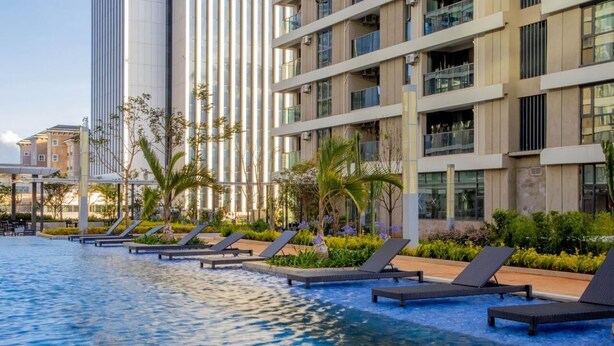Ein modernes Hotel mit Schwimmbad, Liegestühlen und einem gepflegten Garten.