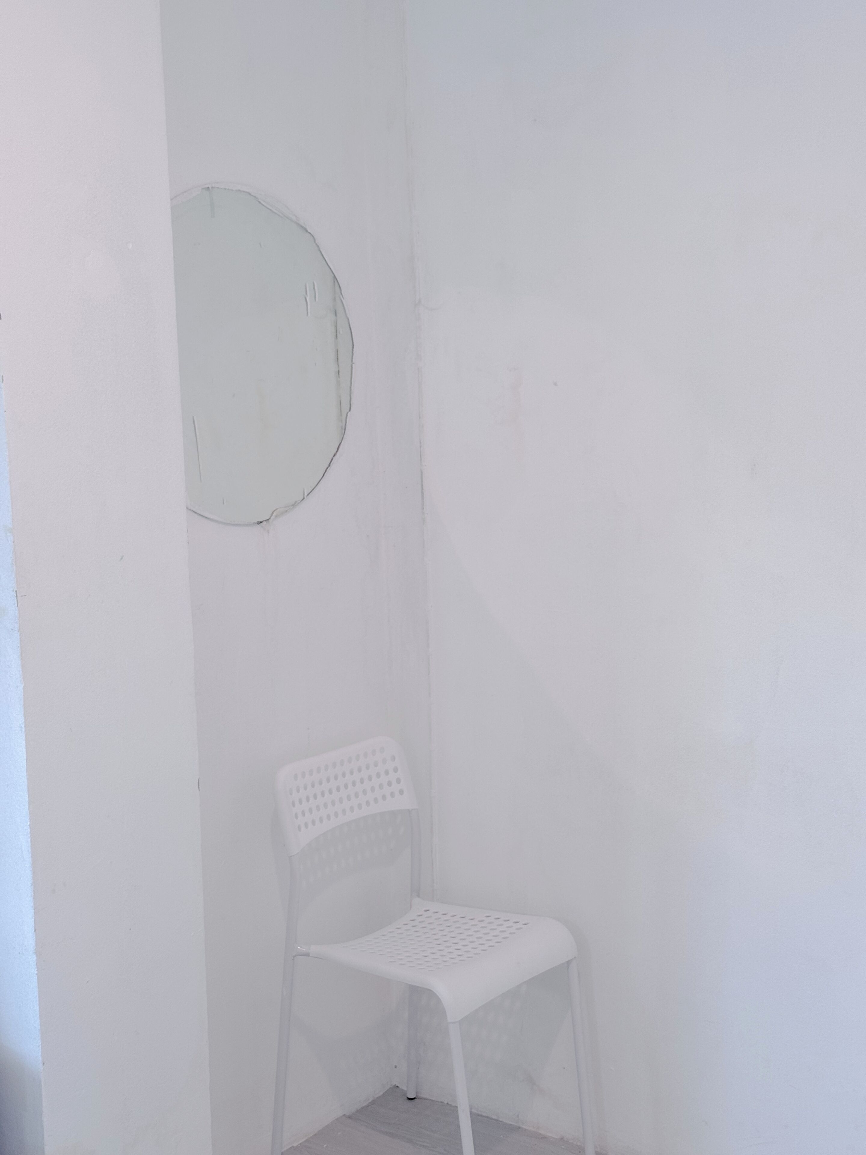 A white plastic chair in a corner of a room with plain white walls.