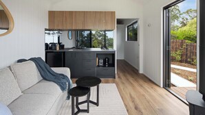 A modern kitchen with wooden cabinets, a dining area with a round table, and a sliding glass door leading to an outdoor area. - Luxury Villa - Firepit - 30min to Most Attractions (Ninderry)