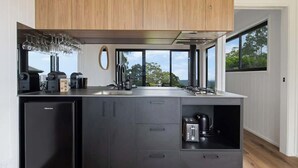 A modern kitchen with a built-in refrigerator, a coffee maker, and a toaster. There is a window providing a view of the outdoors. - Luxe Villa - Ocean Views, 15km to Coolum Beach (Ninderry)