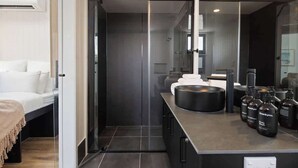 A modern bathroom with a glass shower enclosure, a large mirror, and a countertop with toiletries. - Luxe Villa - Ocean Views, 15km to Coolum Beach (Ninderry)