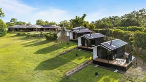 Un moderno complejo residencial con varias casas conectadas por senderos, rodeado de exuberante vegetación.