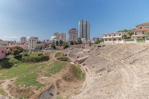 A large outdoor amphitheater with a dirt stage and seating area, surrounded by residential buildings and a tall skyscraper in the background. - Mandalay Suites By The Beach 079 (Rrashbull)