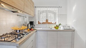 Une cuisine équipée d’une cuisinière à gaz, d’un évier et d’une fenêtre avec un rideau.