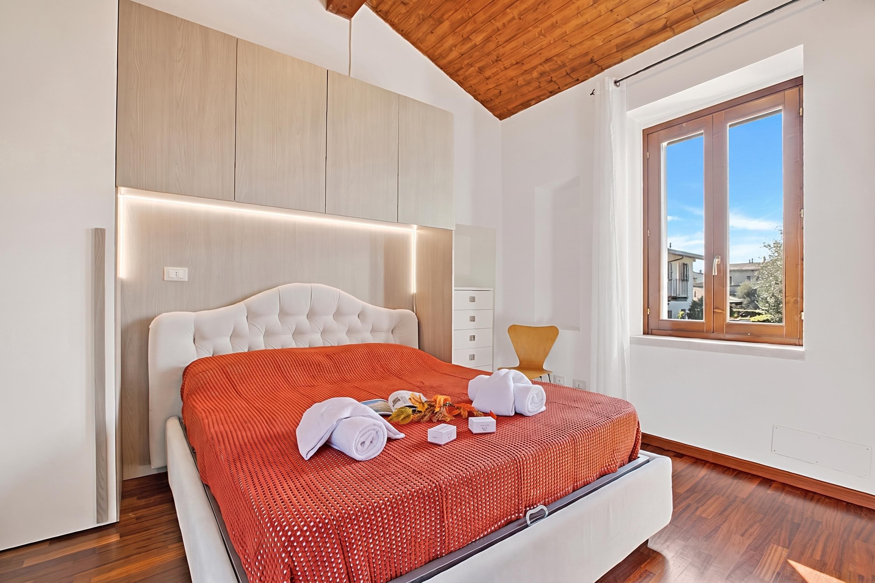 Un dormitorio moderno con una cama grande, cabecera de madera y una ventana con vistas al exterior.