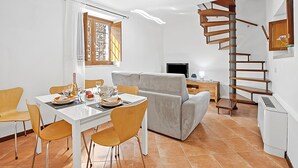 Un espace de vie moderne comprenant un coin repas, un canapé, une télévision et un escalier en colimaçon.