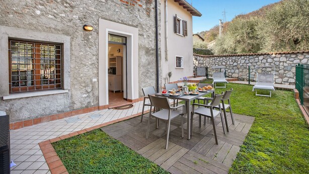 Une terrasse avec une table et des chaises, un mur en pierre et une vue sur une colline.