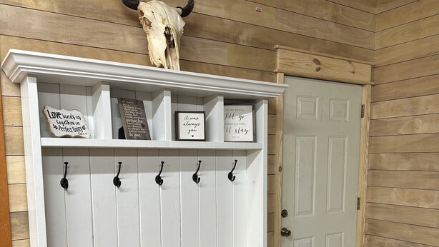 A white wooden bench with a shelf above it, a skull with horns, and a door with a wooden frame. - Escape to the peaceful, Cottage 3:12 at Suttle Ridge in Arkadelphia, AR (Arkadelphia)
