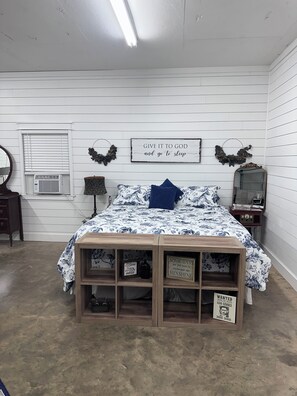 A bedroom with a bed, a dresser, a mirror, and a wall-mounted sign. - Escape to the peaceful, Cottage 3:12 at Suttle Ridge in Arkadelphia, AR (Arkadelphia)