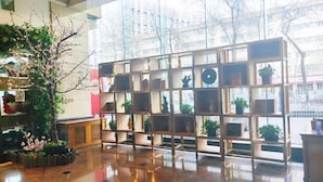 Un interior moderno con suelo de madera, una pared divisoria de vidrio con estanterías y un gran ventanal con vistas a árboles y edificios.