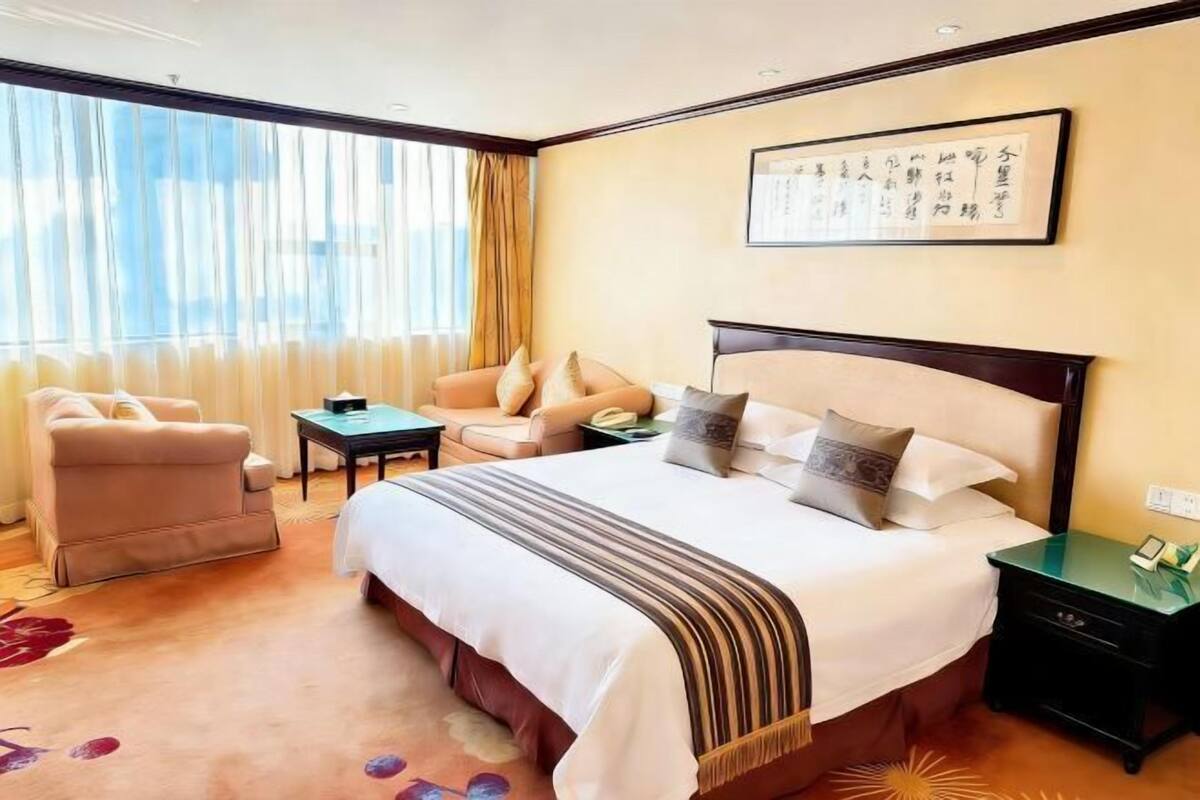 A hotel room with a large bed, a sofa, a desk, and a nightstand.