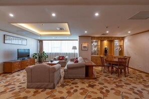 A hotel room with a sofa set, a dining table with chairs, a TV, and a decorative wall piece. - Miramar Urumqi (CCMALL Hongshan Park Times Square Branch) (Urumqi)