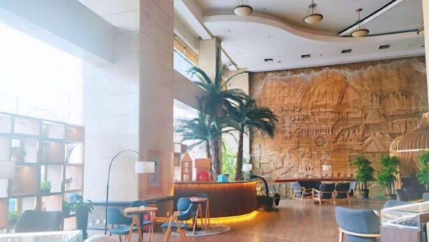 Un hall con mostrador de recepción, zona de estar y un amplio mural en la pared.