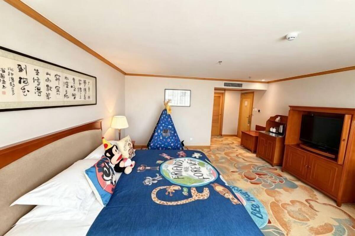 A hotel room with a bed, a television, a wooden cabinet, and a framed picture on the wall.