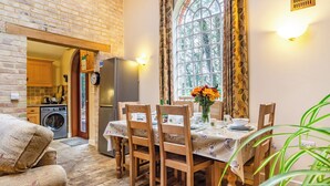 A cozy dining area with a brick wall, a large window with curtains, and a table set for four. - Stearn Cottage-17917 (Bury St. Edmunds)