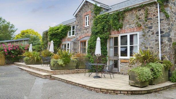 A stone building with a patio area, outdoor seating, and greenery. - Virginia Cottage - 28108 (Bovey Tracey)