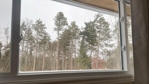A window with a view of a forest. - Whispering Pines Resort (Grand Bend)