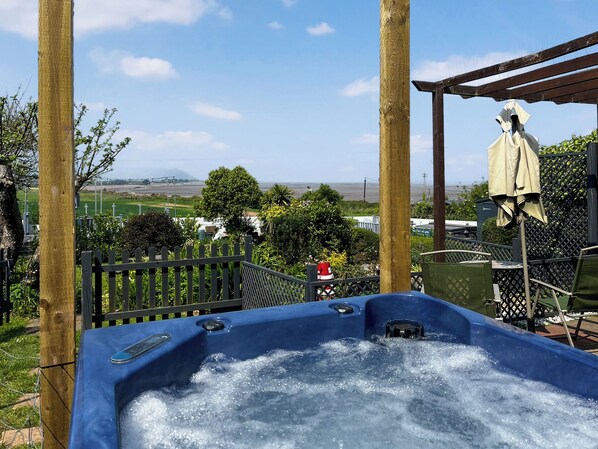 A hot tub with a view of a cemetery and a distant landscape. - Anchors Away - 29566 (Blue Anchor, near Minehead)
