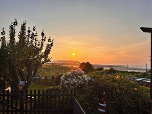 Ein Sonnenuntergang mit Holzzaun, Feuerhydrant und einem Garten mit weißen Blüten.