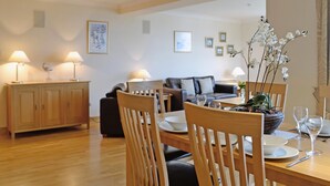 A dining area with wooden furniture, a sofa, and a table set for a meal. - Links Apartment 8 - 29971 (Brora)