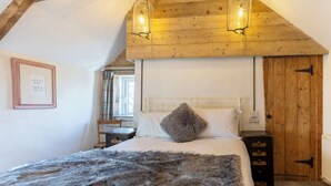 Une chambre avec un plafond en bois, un lit recouvert d’une couverture moelleuse, une table de chevet et une citation encadrée accrochée au mur.