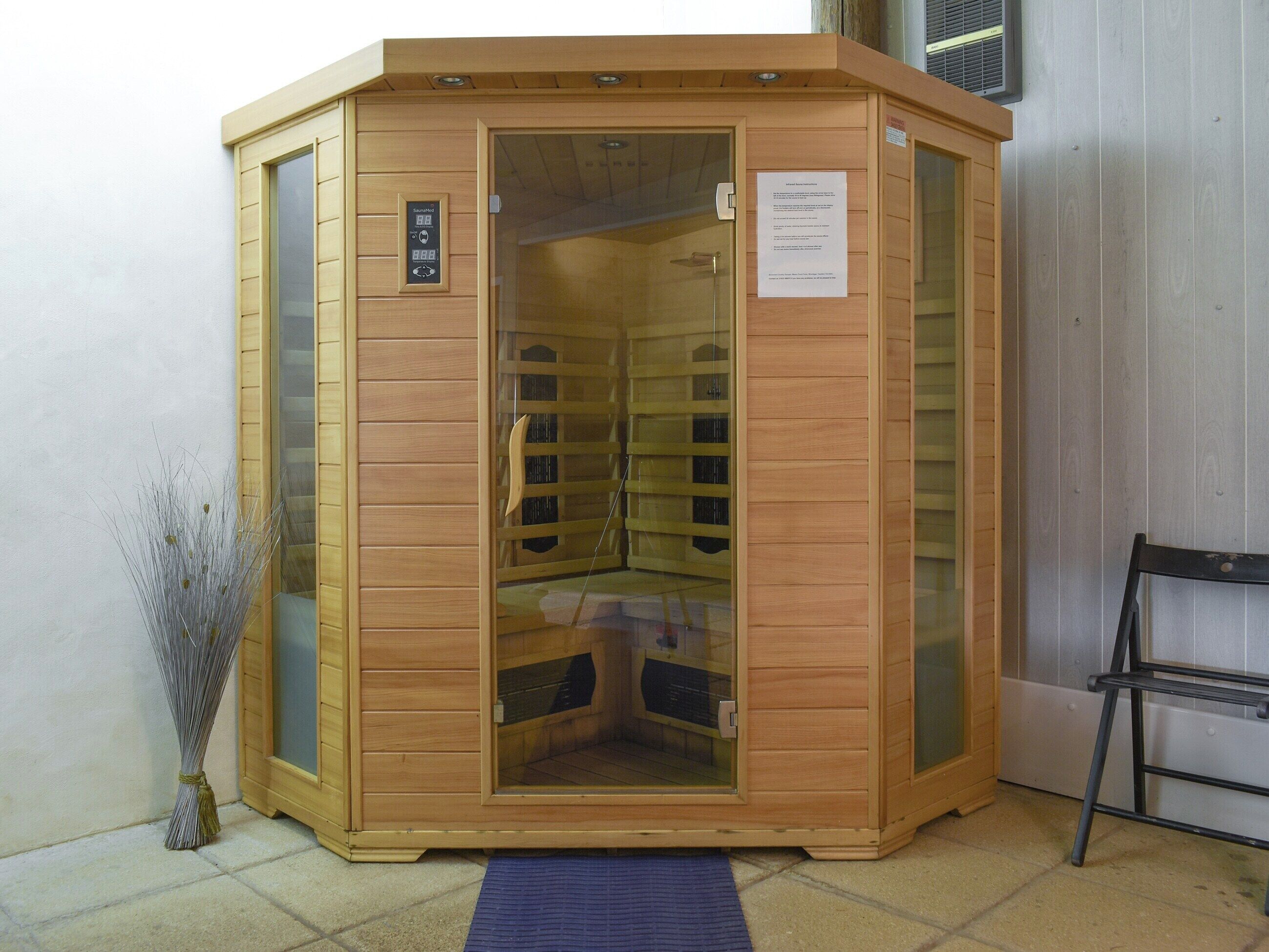 A sauna with a wooden exterior, glass doors, and a control panel.