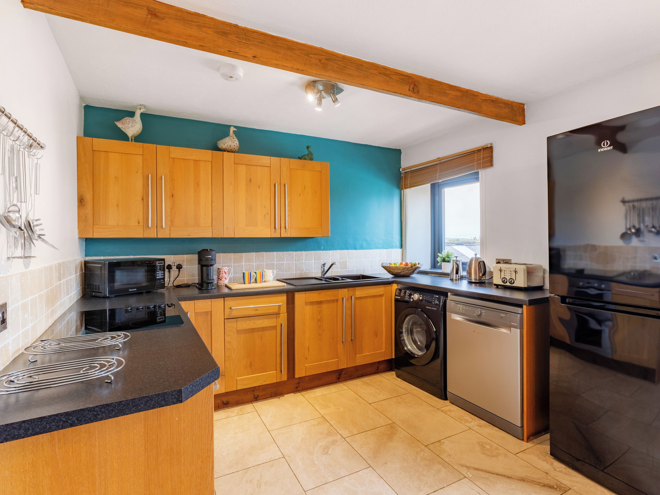 Una cucina moderna con mobili in legno, forno integrato, lavastoviglie e forno a microonde.