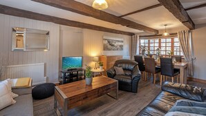Ein gemütliches Wohnzimmer mit einem Holztisch, einer Ledersofa und einem Essbereich mit Tisch und Stühlen.