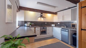Eine moderne Küche mit weißen Schränken, einer schwarzen Fliesenfassade und Holzbalken an der Decke.