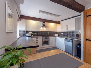A modern kitchen with white cabinets, a black tiled backsplash, and wooden beams on the ceiling. - 2 bedroom accommodation in Wrantage, near Taunton (Wrantage, near Taunton)