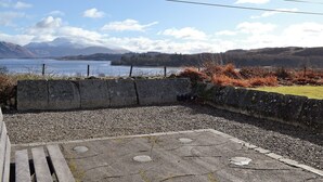 Un mur de pedra amb un camí de grava que condueix a una banca.