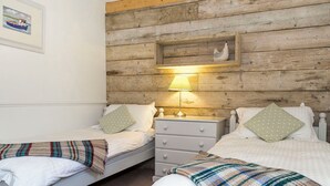 A room with two beds, a wooden headboard, a nightstand with a lamp, and a framed picture on the wall. - 2 bedroom accommodation in Marhamchurch, near Bude (Marhamchurch, near Bude)