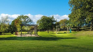 Een park met een picknickplaats, schommelen en een pergola.