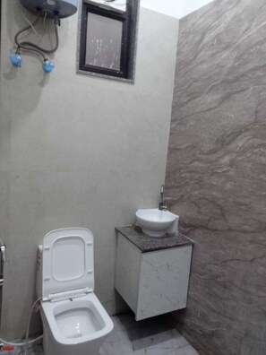 Une salle de bain avec des toilettes, un lavabo et un mur en marbre.