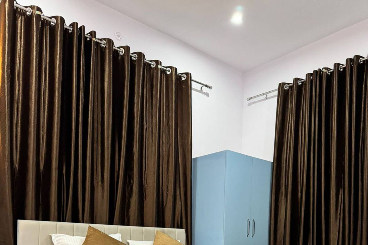 Un dormitorio moderno con cama, mesita de noche, armario y cortinas oscuras.