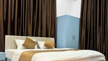 Un dormitorio moderno con cama, mesita de noche, armario y cortinas oscuras.