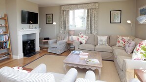 A living room with a fireplace, a sofa set, a coffee table, and a bookshelf. - 4 bedroom accommodation in Portpatrick (Portpatrick)