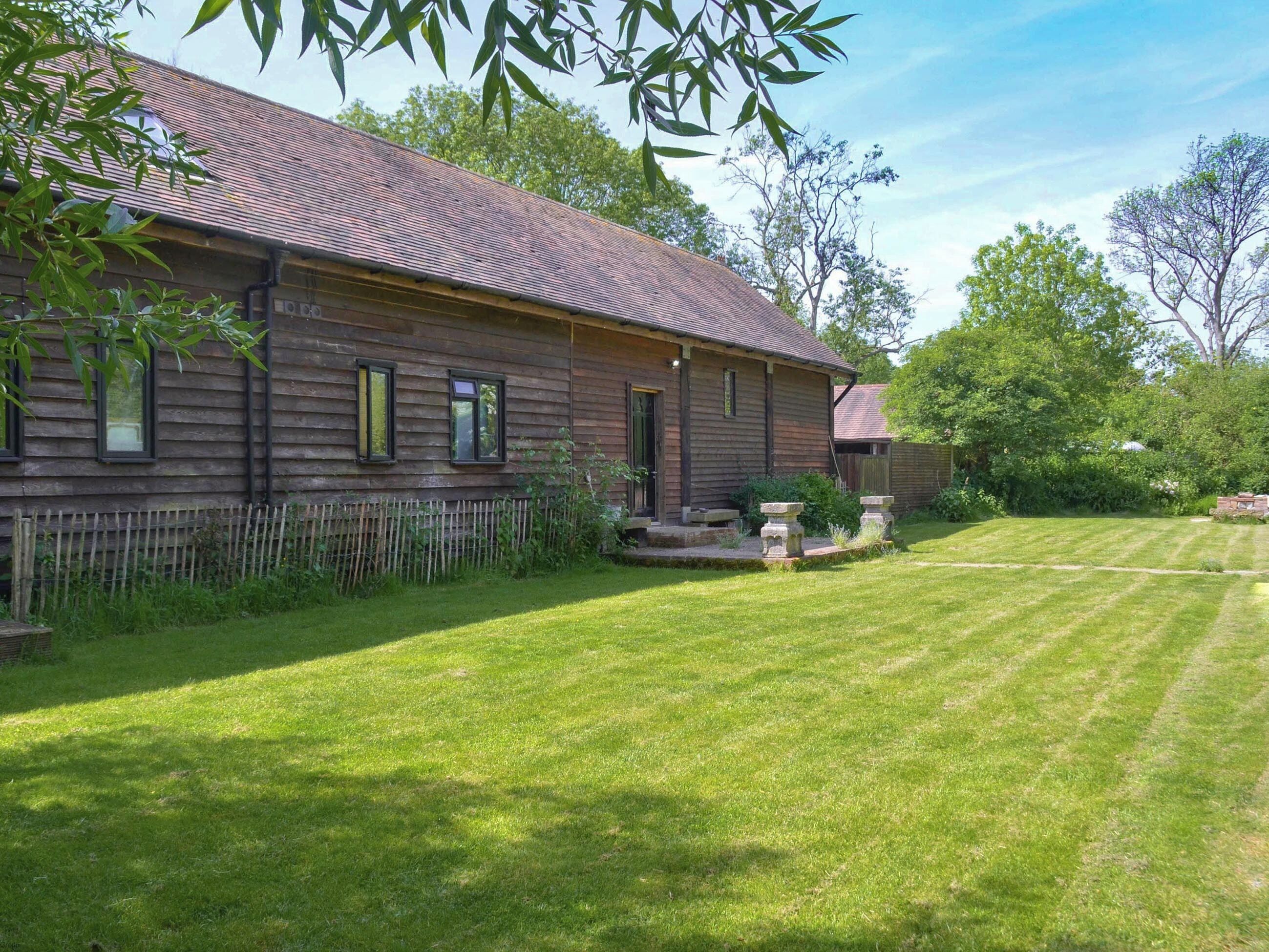 Une maison en bois avec un toit en pente, une cour clôturée et une pelouse bien entretenue.
