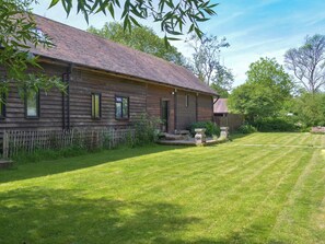 A wooden house with a sloped roof, a fenced yard, and a well-maintained lawn. - 4 bedroom accommodation in Hardham (Hardham)