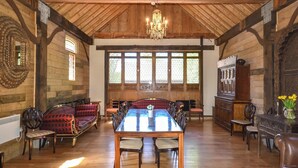 Un comedor amplio con un alto techo de madera, una araña y una gran mesa de madera rodeada de sillas.