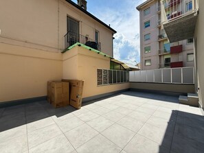 Un immeuble résidentiel doté d’un patio carrelé, d’un balcon et offrant une vue sur les bâtiments voisins.