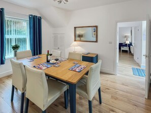 A dining area with a wooden table, chairs, and a bottle of wine. - 3 bedroom accommodation in Minehead (Minehead)