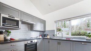 Een moderne keuken met grijze kastjes, een inbouwoven, een magnetron en een raam met uitzicht op de omgeving.