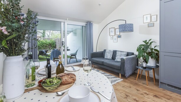 Een moderne woonkamer met een eethoek, een grijze bank en een eettafel gedekt voor twee personen.