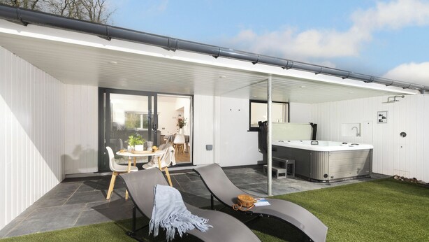 A modern outdoor patio with a lounge area, a hot tub, and a dining setup. - Little Dunley Cottages - Hazel (Bovey Tracey)