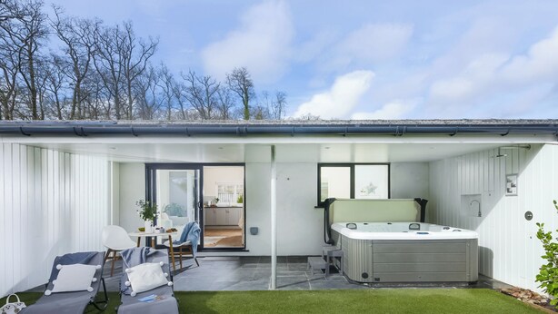 Un espace de vie extérieur moderne comprenant un jacuzzi, des chaises longues et une terrasse.