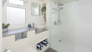 Une salle de bain moderne avec une douche à parois de verre, un lavabo et une fenêtre.